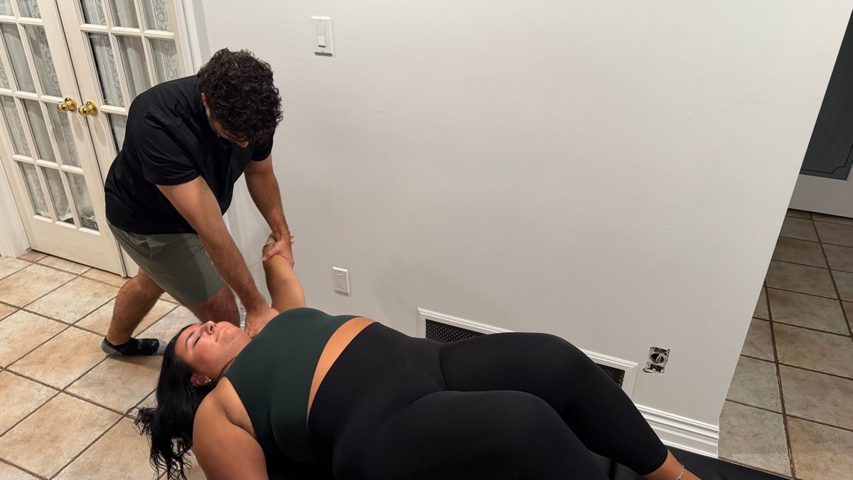 Dr. Alex providing an assisted shoulder stretch during a home visit