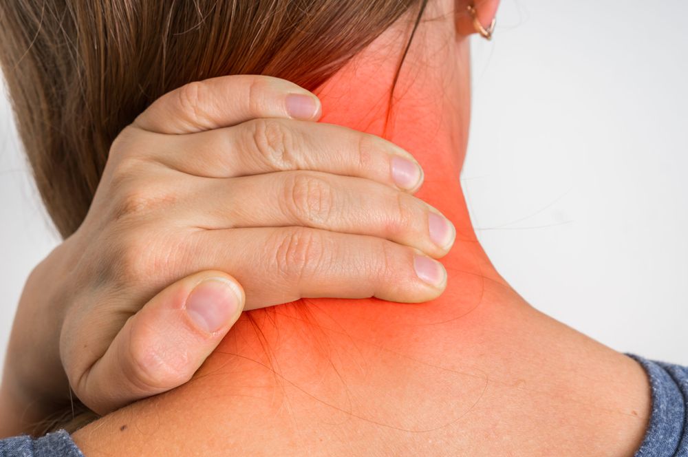 Woman holding the back of her painful neck, a common reason for neck pain treatment in Oakville